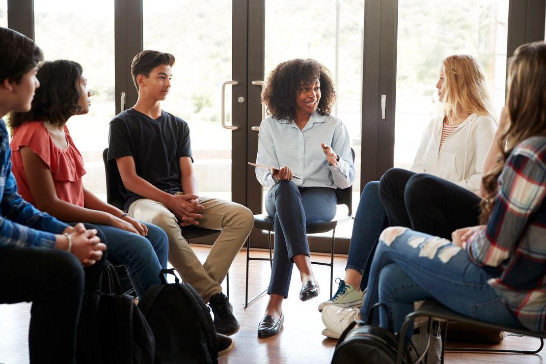 Female Tutor Leading Discussion Group Amongst High School Pupils